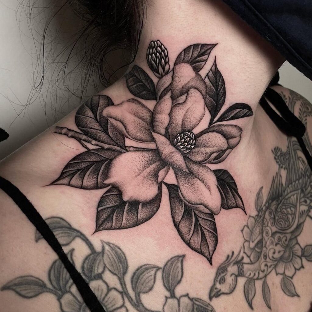 A large black ink magnolia blossom tattoo with thick outlines on a person's neck.