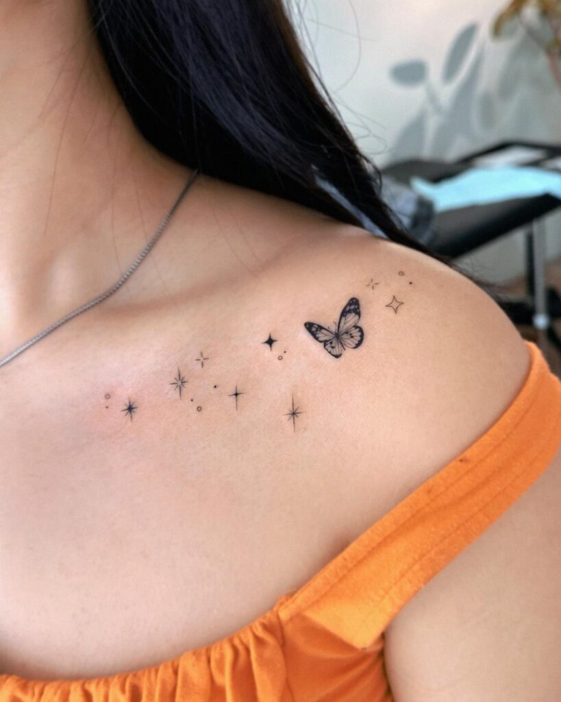 A small black butterfly tattoo with tiny stars on a person's collarbone area.