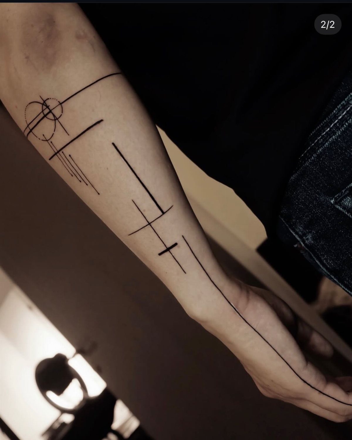 A minimalist geometric line tattoo stretching from a person's forearm down to their hand.
