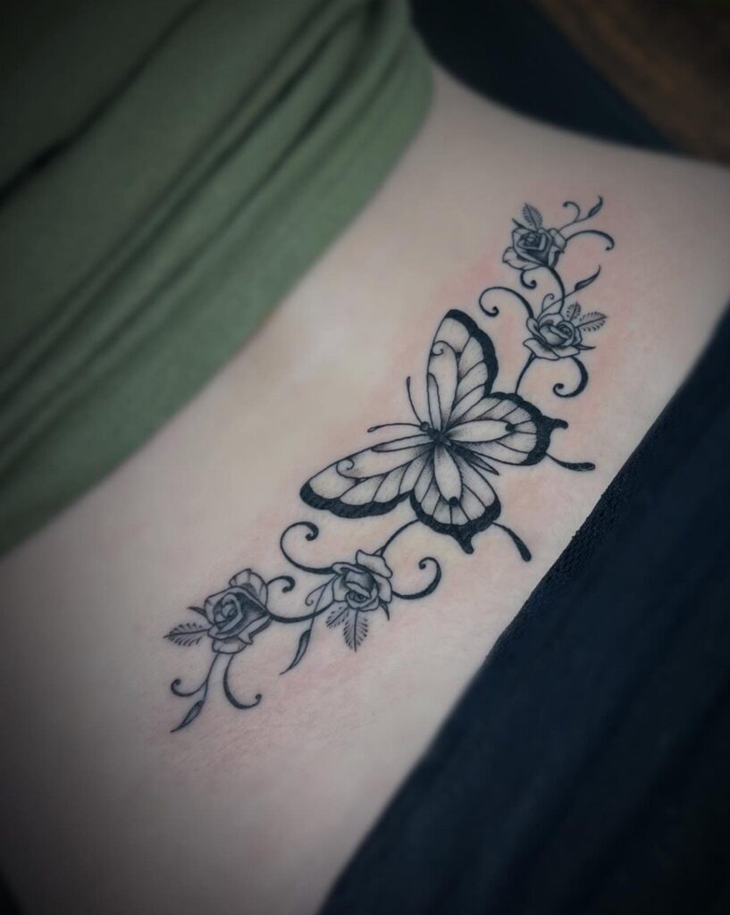 A black ink butterfly and rose tattoo design on a person's skin.