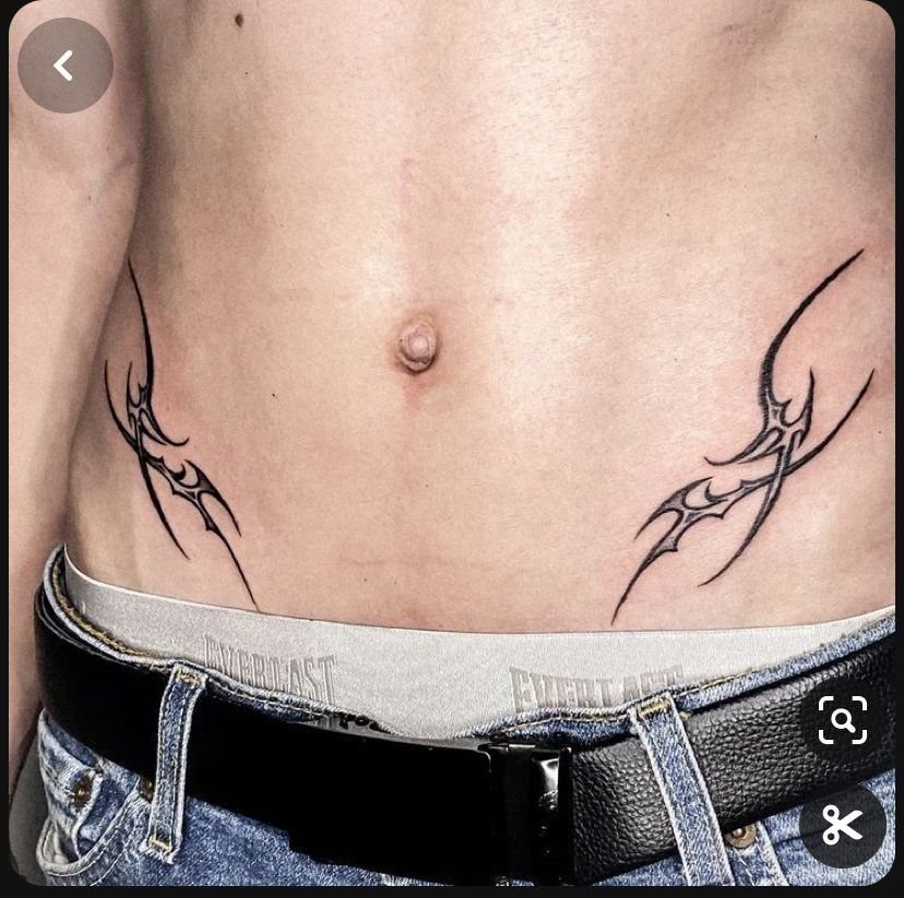 Two black tribal tattoos placed on the lower abdomen near the hip bones.